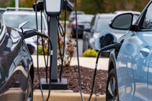 An,Electric,Vehicle,Recharges,At,A,Station,While,Its,Owner